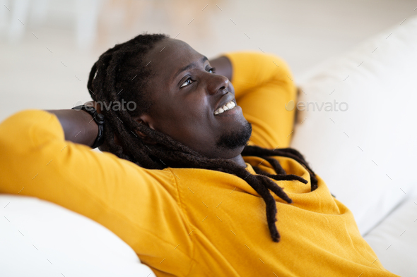Home Rest. Portrait Of Smiling Young Black Man Leaning Back On Couch