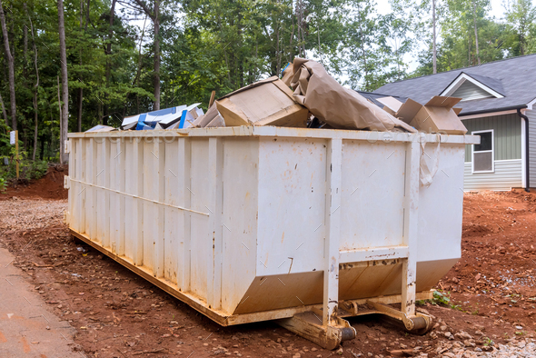 A rubbish removal container on of a house underneath an industrial building is used for waste