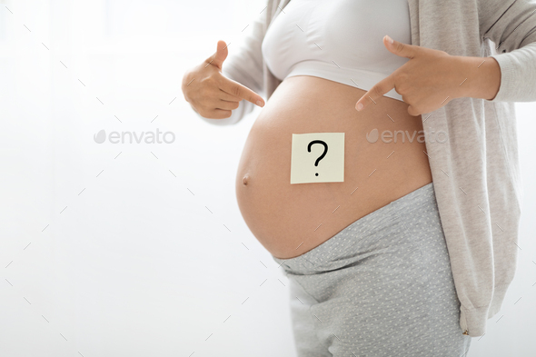 Pregnant woman with paper sticker with question mark on tummy - Stock Photo - Images