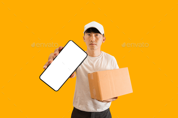 Young Asian delivery man wearing cap with white blank t-shirt holding smartphone and parcel post box