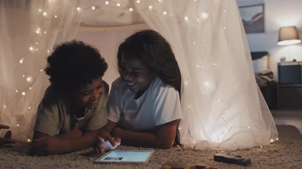 Siblings Using Tablet in Handmade Tent alt