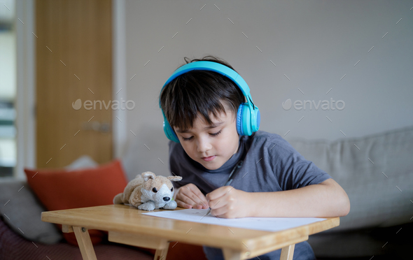 kid wearing headphones and listening to music drawing or sketching on paper,Child doing homework