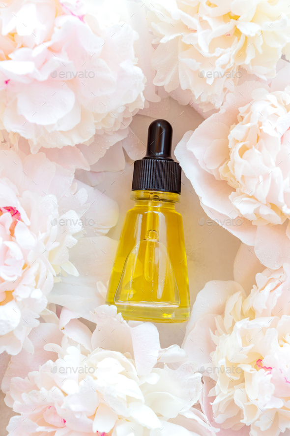 fresh peony flowers background and bottle with cosmetic oil for branding. Wellness, home skin care