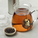 Glass teapot with a metal tea infuser and Ostfriesen tea in front - PhotoDune Item for Sale