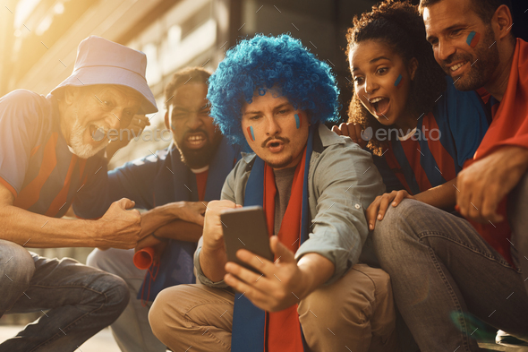 Sports fans cheering while watching soccer match on smart phone.