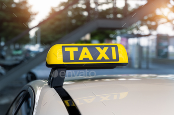 Close-up detail yellow taxi symbol on cars roof stand waiting at parking of airport terminal or