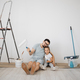 Cheerful caucasian man father and his cute little girl daughter sitting on floorwith paint rollers - PhotoDune Item for Sale
