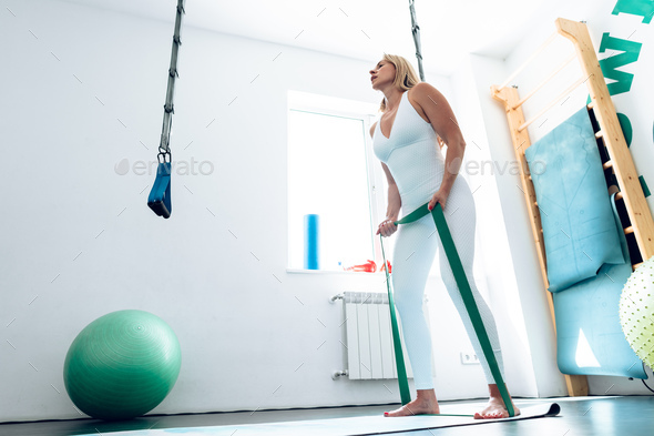 Middle-aged woman during her fitness workout at gym with rubber resistance band