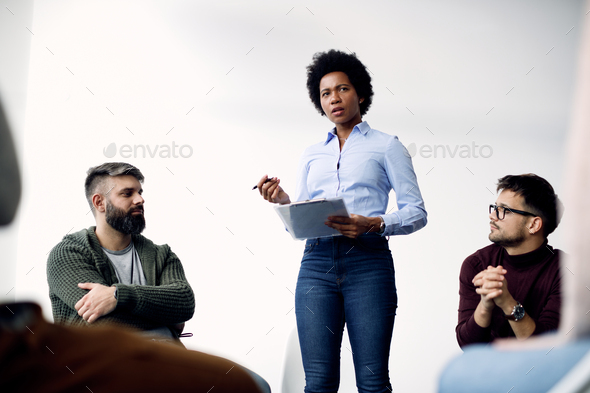 Below view of black female psychotherapist talking during group therapy.