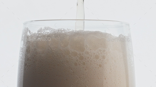 Foamy beer stream pouring glass closeup. Unfiltered drink filling glassware