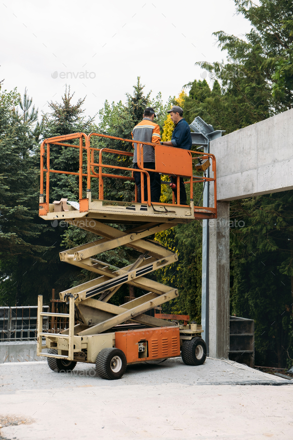 Scissor Lift Platform with workers on a construction site near the wall