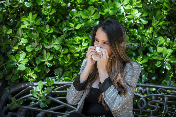 Woman with hay fever sneezing into tissue