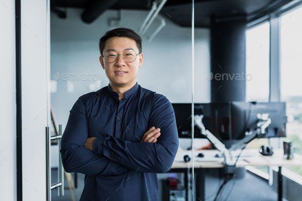 Portrait of successful Asian programmer, team leader company owner smiling and looking at camera