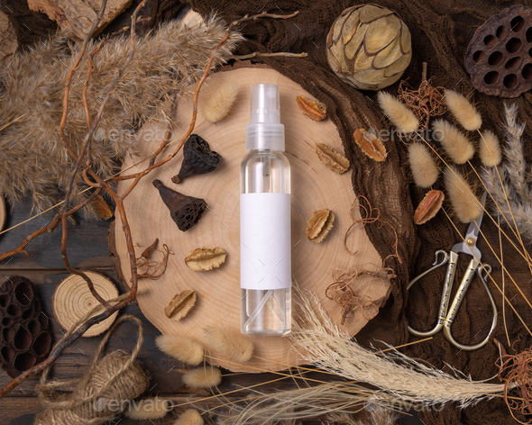 Cosmetic spray bottle on wood near natural boho decorations top view. Label Mockup