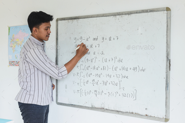 Teacher writing math lesson on whiteboard at the classroom