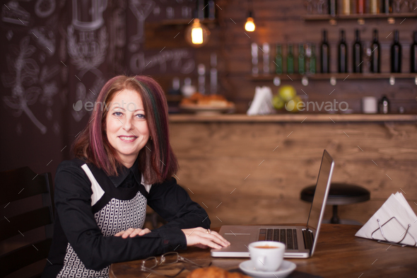 Smiling businesswoman with a laptop in font of her - Stock Photo - Images