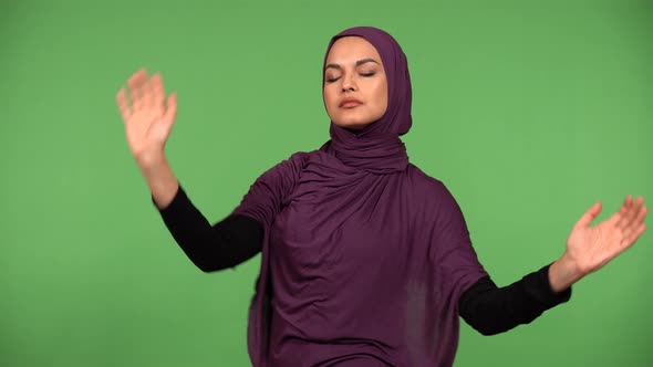 A Young Beautiful Muslim Woman Dances and Waves Hands to Slow Music  Green Screen Background alt