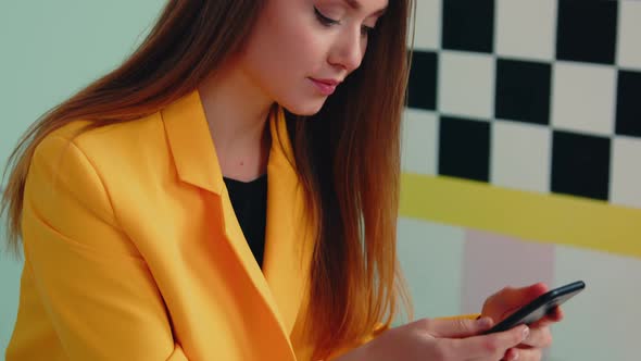 Young Lady In Yellow Jacket Is Texting Message In Mobile Phone