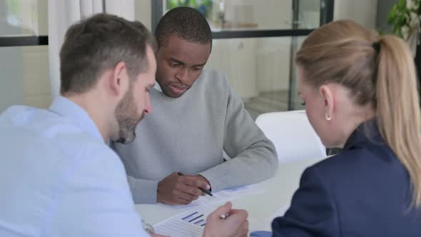 Male and Female Business Person Discussing Documents in Office alt