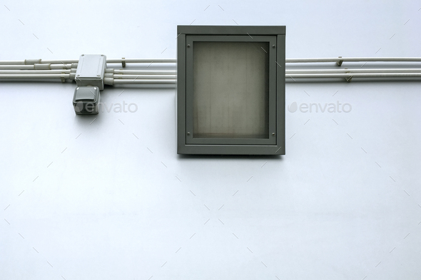 One square LED industrial street flood light with wires and switch, on street wall background.