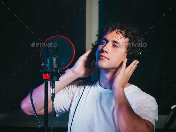 Male vocal artist with curly hair singing alone.handsome singer man writing song in studio.