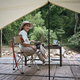 Peaceful asian woman sitting on folding chair near river bank during camping in nature park.  - PhotoDune Item for Sale