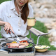Female tourist grilling meat on metal stove during camping in nature park. - PhotoDune Item for Sale