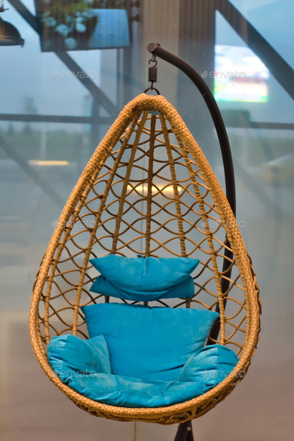 The hanging chair is egg braided. With blue pillows. View from the front.