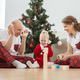 Toddler child with cochlear implant plays with parents under christmas tree in new year and winter - PhotoDune Item for Sale