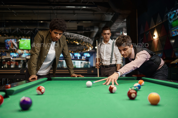 Company of handsome young guy playing in pool