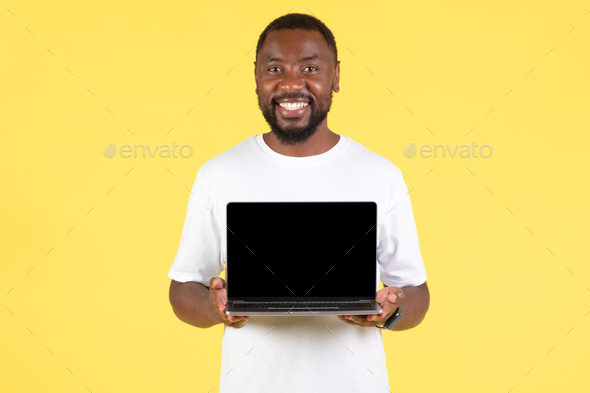 Happy Black Guy Showing Laptop Blank Screen Over Yellow Background