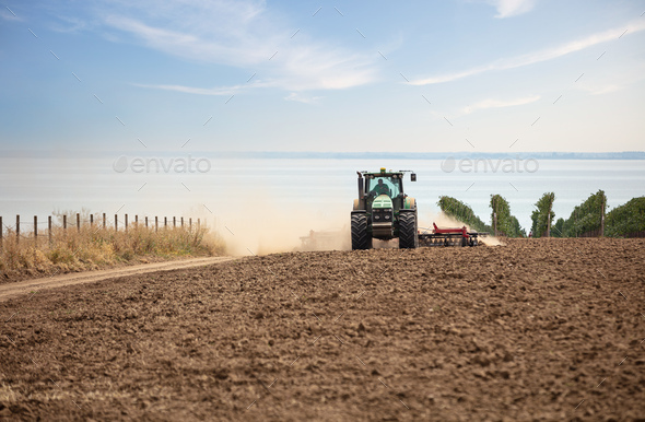 Farmer in tractor working in field on summer day - Stock Photo - Images