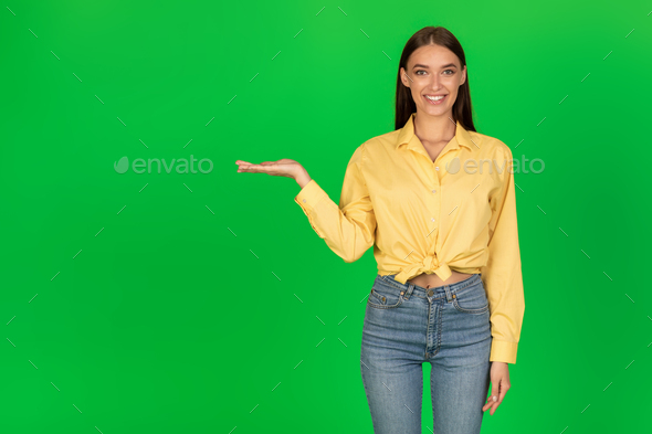 Happy Lady Holding Invisible Object On Hand Over Green Background - Stock Photo - Images