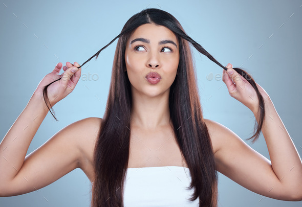 Studio shot of a beautiful young woman showing off her long silky hair against a blue background