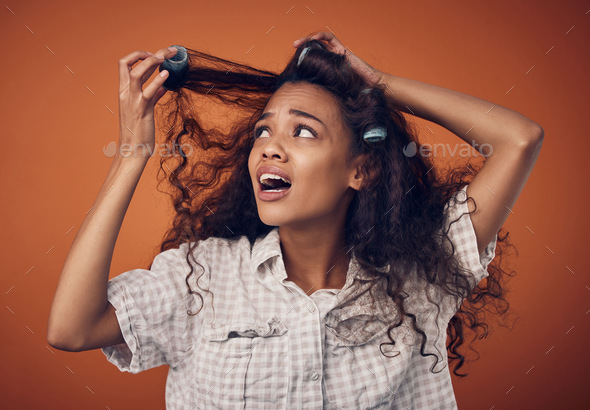 Am I even doing this right. Shot of a woman pulling hair rollers out of her hair.