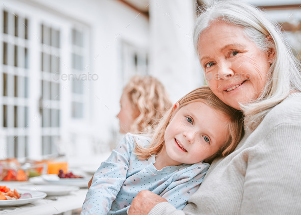 Home is where you are loved. Shot of a grandma and granddaughter cuddling at a table outside.