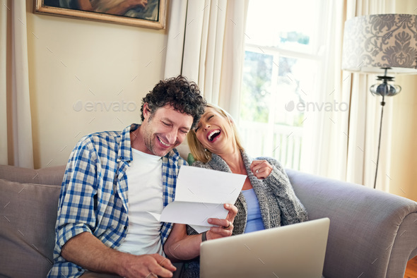 That was a laugh. Shot of a mature couple laughing while going over the expenses at home.