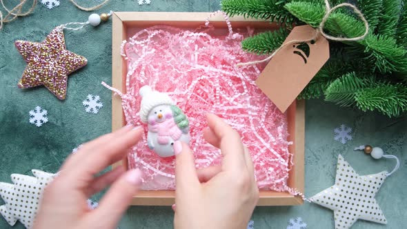 Hands putting Christmas toys in a gift box. New Year's decor, DIY gift wrapping.