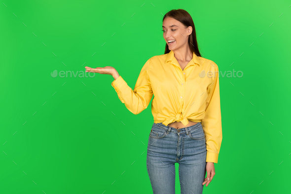 Cheerful Woman Holding Invisible Object On Hand Over Green Background - Stock Photo - Images
