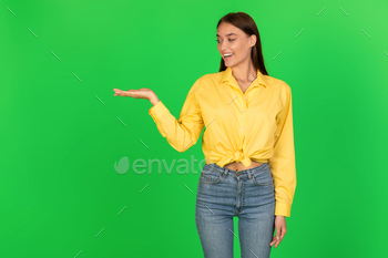 Cheerful Woman Holding Invisible Object On Hand Over Green Background
