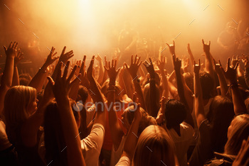 Die hard fans. Rearview of a crowd at a music gig with their hands raised in the air.