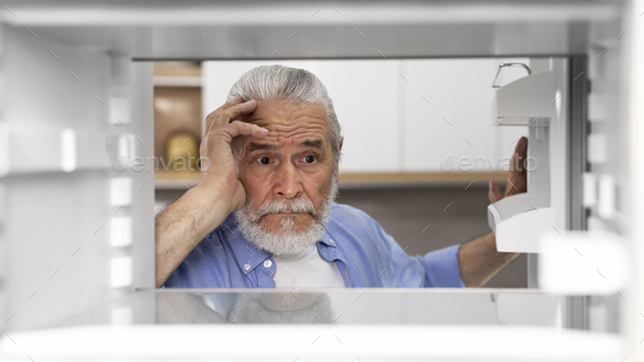 Portrait Of Hungry Elderly Man Searching For Food In Empty Fridge