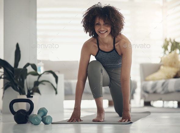 Shot of an attractive young woman practising yoga in her living room and holding a high lunge pose
