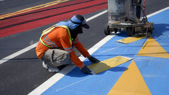 Road workers with thermoplastic marking machine paint traffic sign and bicycle lane on asphalt road