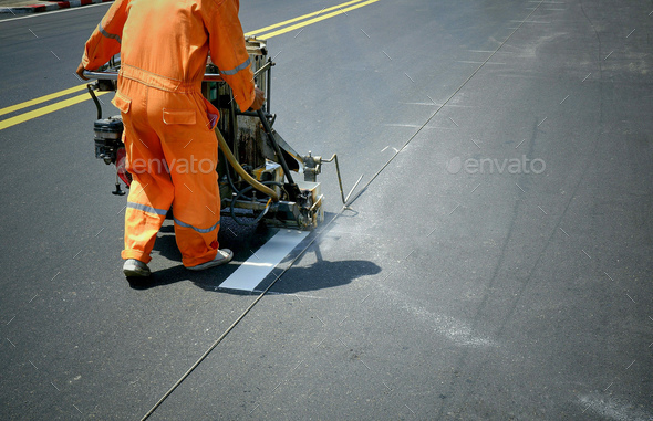 road worker using thermoplastic spray road marking machine to painting white line on asphalt street