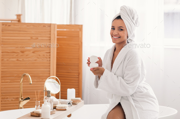 Happy Woman Opening Moisturizer Jar Caring For Skin In Bathroom