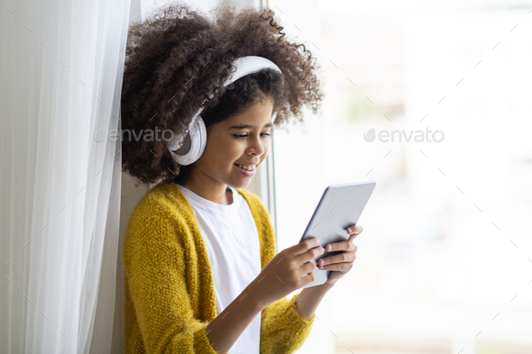 Closeup of cheerful black girl using digital pad and headset