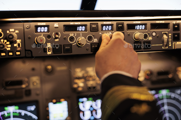 Male pilot pushing buttons to fix altitude level on control panel command