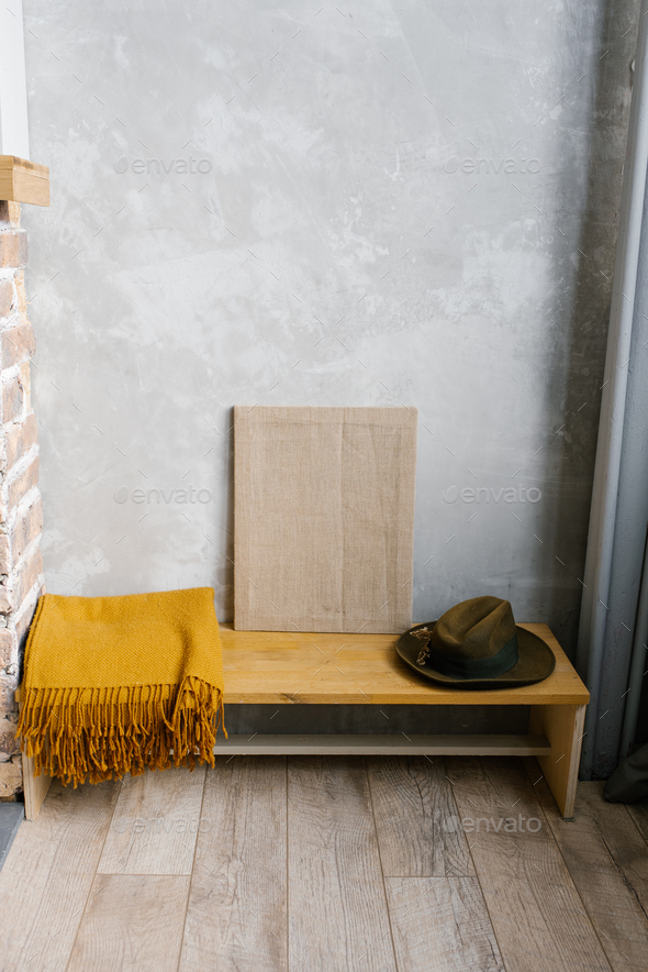 Brown plaid, felt hat and canvas on a wooden bench in the interior of a Scandinavian house