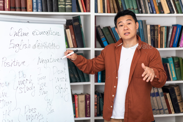 Asian Tutor Talking Pointing At Whiteboard Having Remote Class Indoors